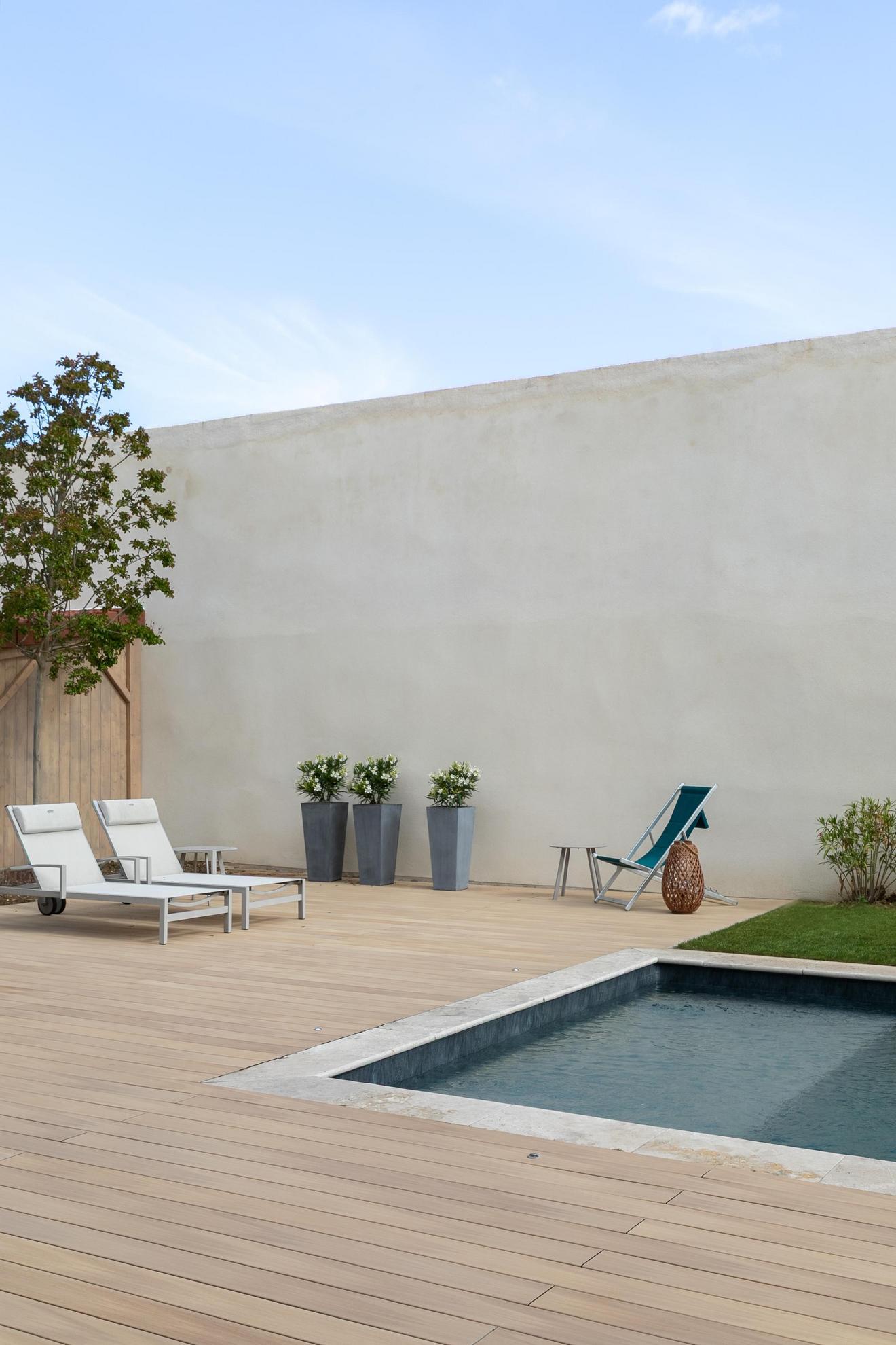 Two loungers on a Silvadec Nuances Light Oak decking with a coped pool