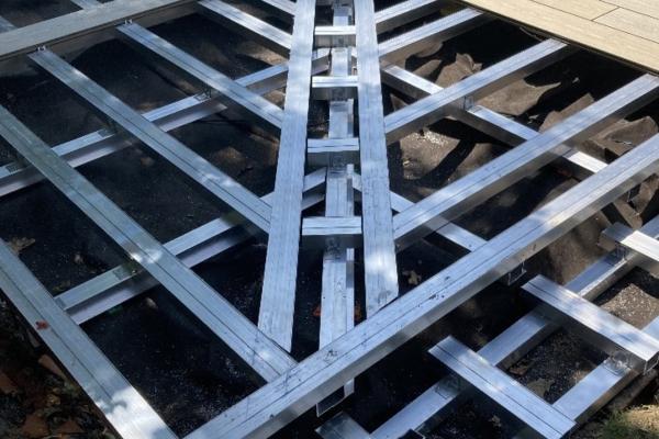 Structure de terrasse en lambourdes aluminium Silvadec au bord d'une piscine, supportant des lames de bois composite, montrant le système de fixation métallique robuste et résistant à l'eau