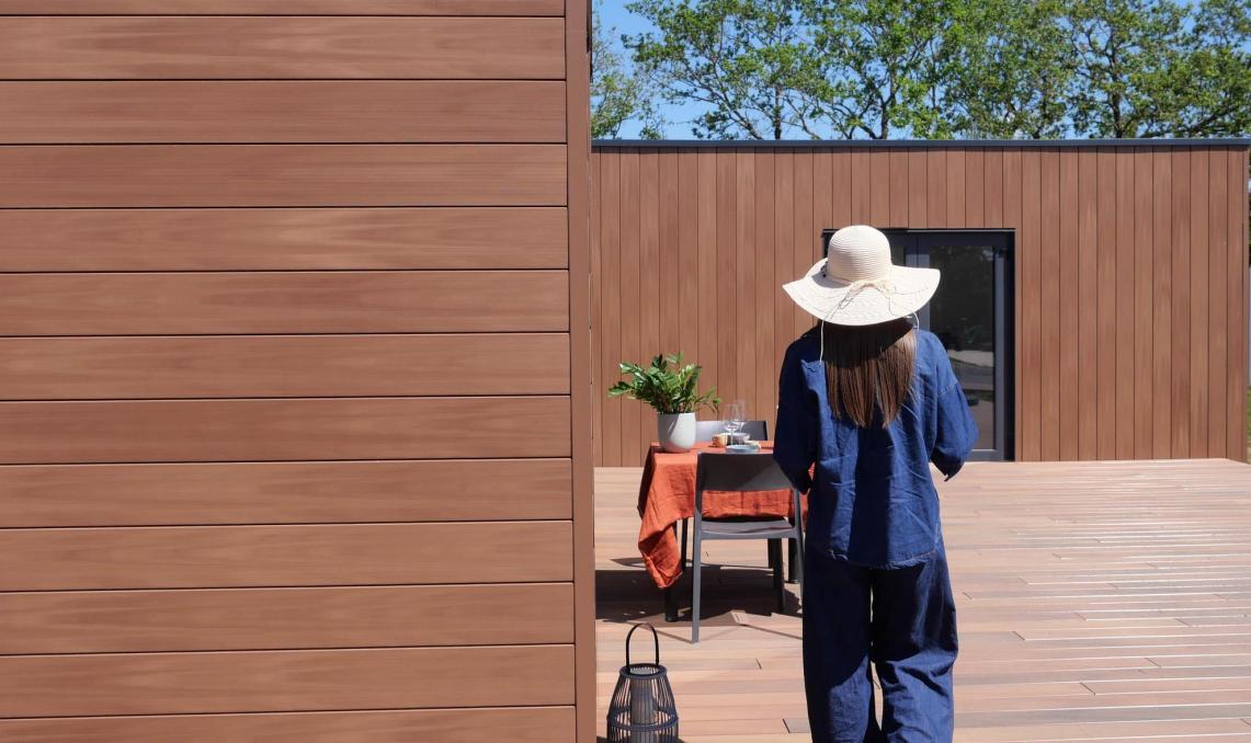 Young woman in a hat walks towards a table and Atmosphere cladding 175 Brown Sun Silvadec 
