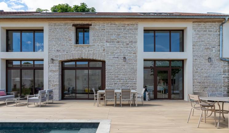 Terrasse composite Nuances Chêne clair autour d'une piscine, devant une ancienne cave en pierre rénovée à Beaune